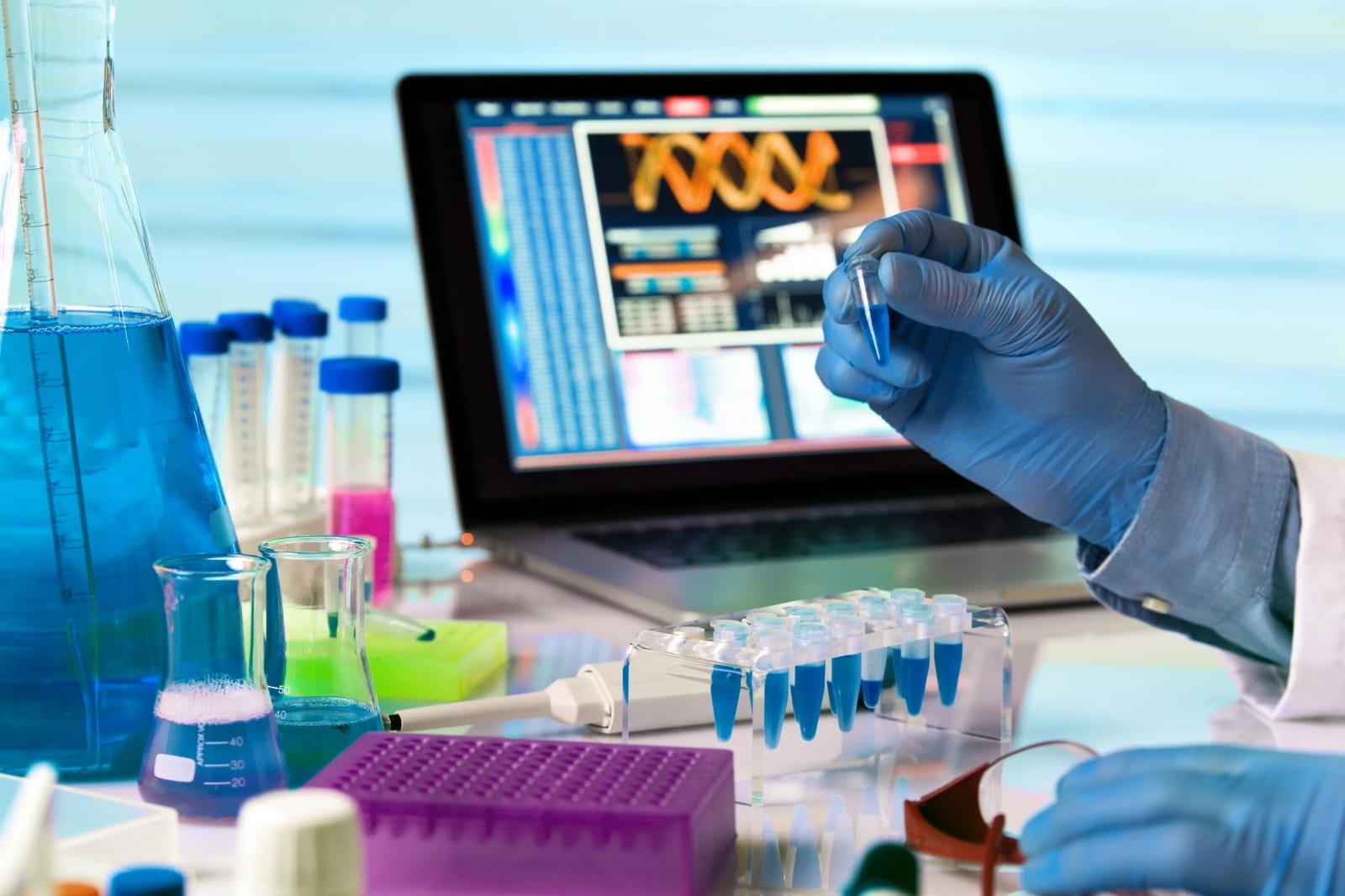 Gloved hand holding a sample tube beside a DNA display